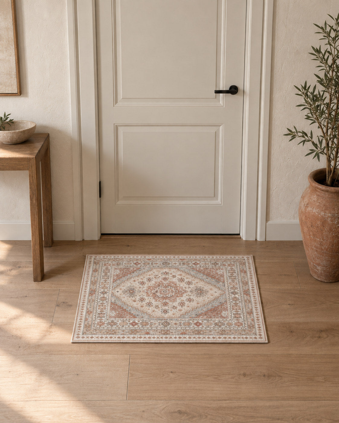Tapis d'entrée persan vintage beige et terracotta, posé devant une porte