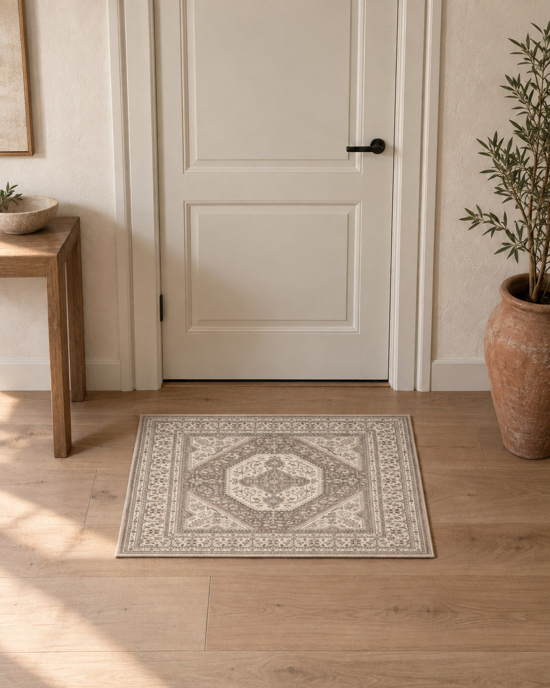 Tapis d'entrée persan vintage beige et gris, posé devant une porte